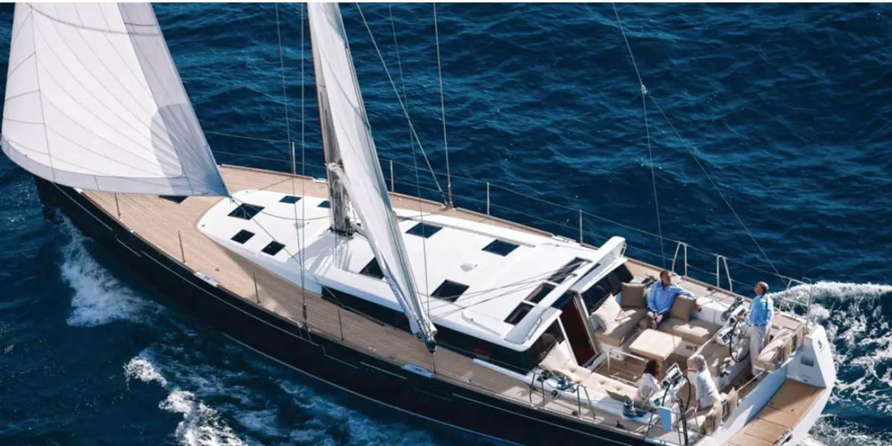 A white sailing yacht seen from above with its sails set on deep blue water