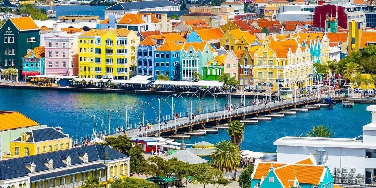 The pastel houses of Willemstad's Handelskade and the floating bridge seen from above across the harbor