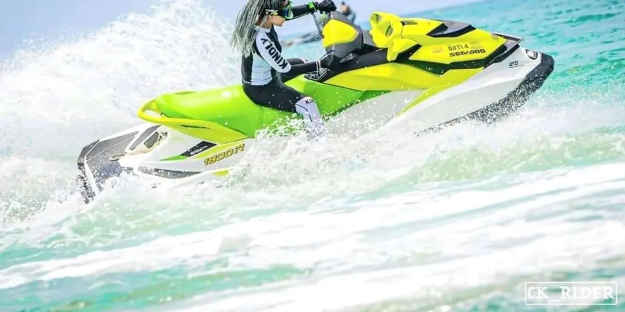 A rider on a green jet ski throwing up white spray