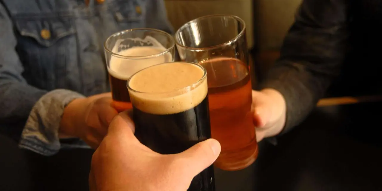Hands raising glasses of stout, ale and cider in a pub