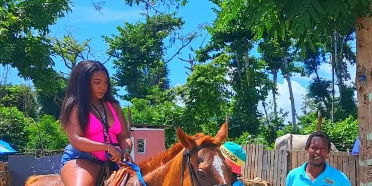 A woman in a pink top riding a chestnut horse