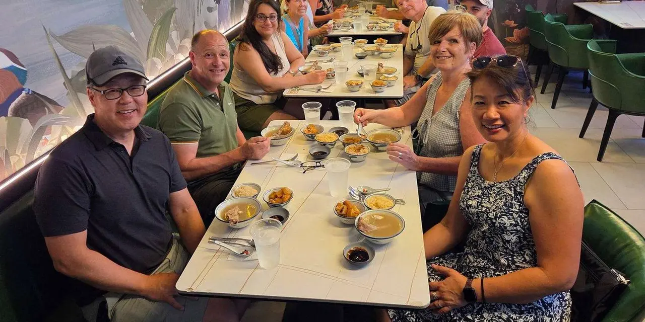 A tour group seated at a long table with plates of local dishes in a restaurant