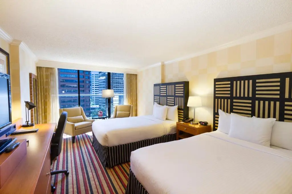 A Pinnacle Hotel Harbourfront room with two queen beds, striped headboards and a window onto downtown towers