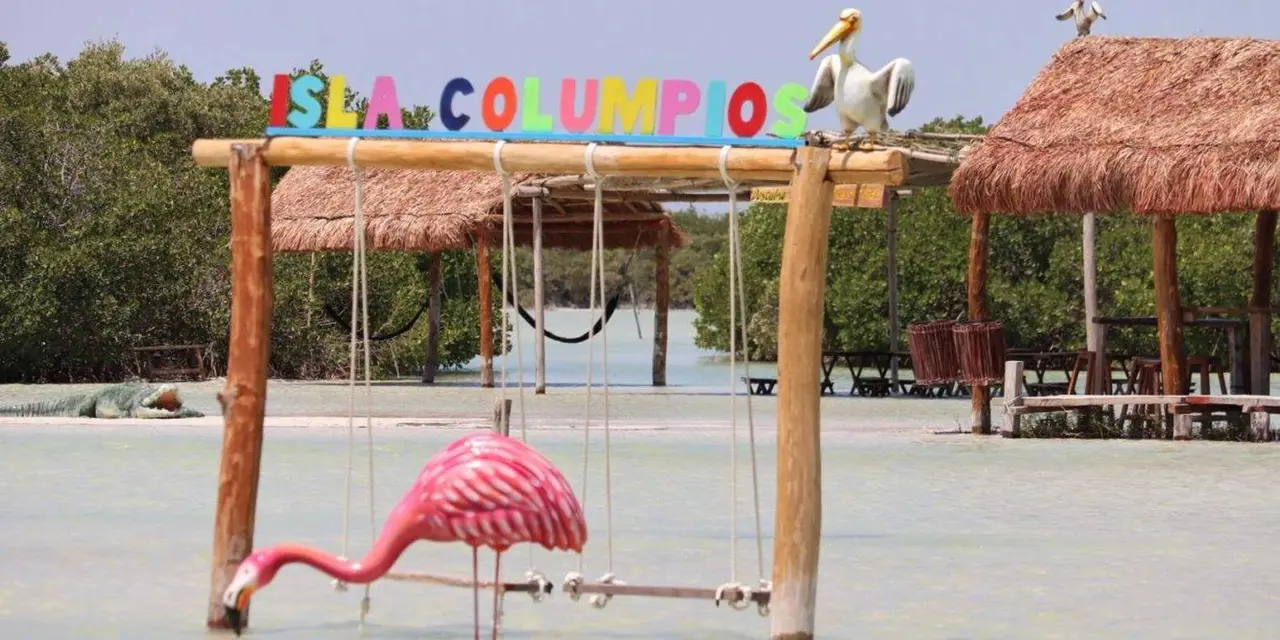 Isla Columpios letters above wooden swings in shallow water with a pink flamingo figure