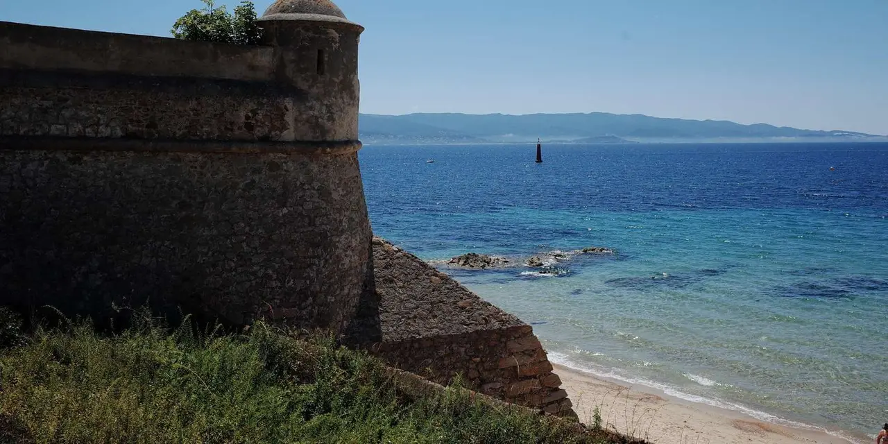 The stone bastion of Ajaccio's citadel above a beach and turquoise water