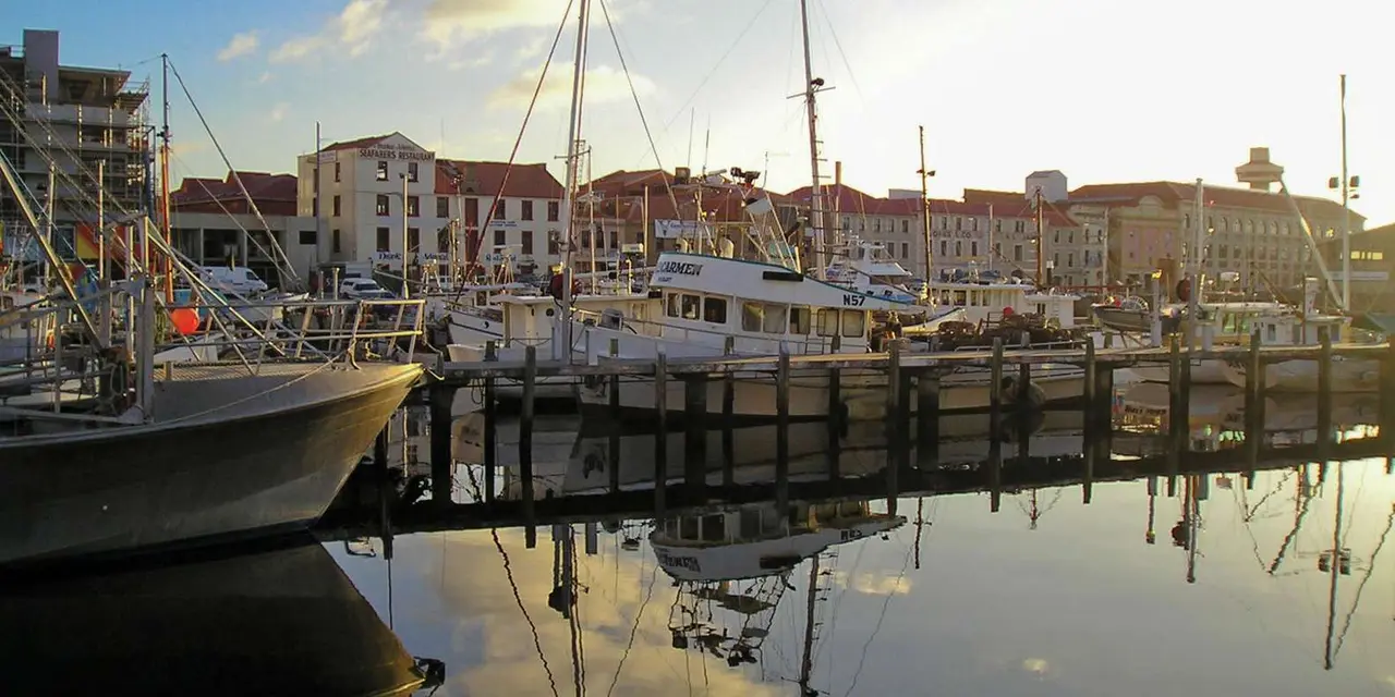 Boats moored at a timber wharf in front of Hobart's sandstone warehouses