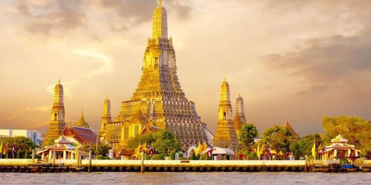 Wat Arun's spires glowing gold against a sunset sky