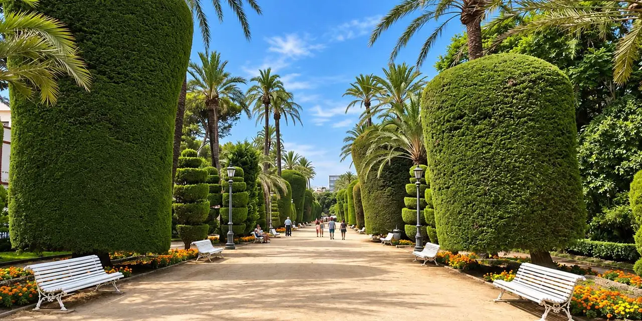 A wide sunny garden path lined with tall palm trees and clipped round topiary hedges, with benches at the edge and a few people strolling