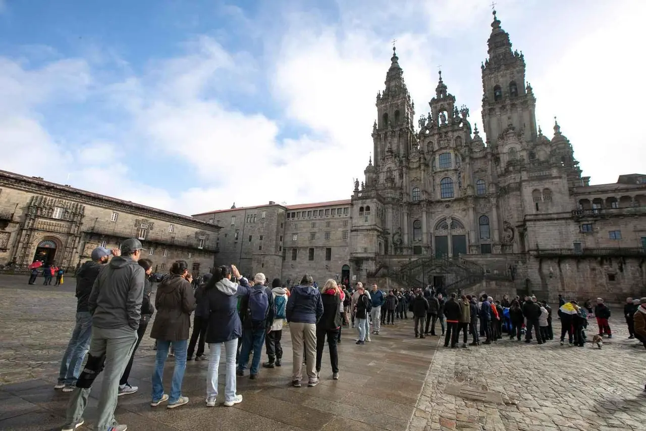 A crowd gathered in a wide stone square in front of Santiago de Compostela cathedral's ornate baroque towers