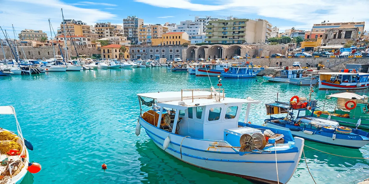 Colourful wooden fishing boats moored in the old harbour with stone Venetian arches behind