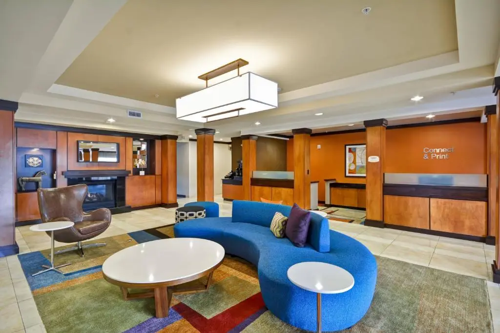 The Fairfield Inn lobby with a curved blue sofa, round white tables and the front desk behind