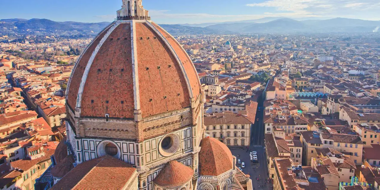 The terracotta dome of Florence's cathedral seen from above, with the city's rooftops stretching away to the hills