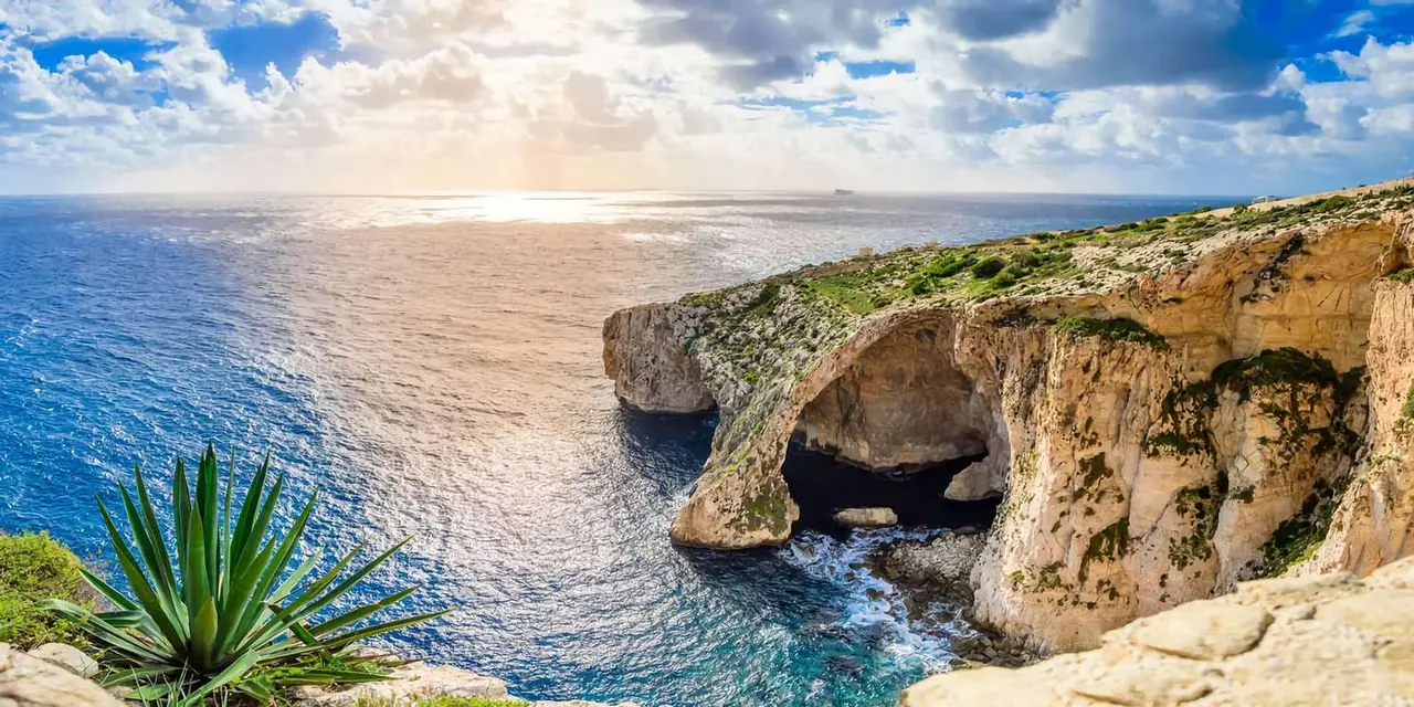 An aerial view of the Blue Grotto's sea arch and cliffs above clear blue water