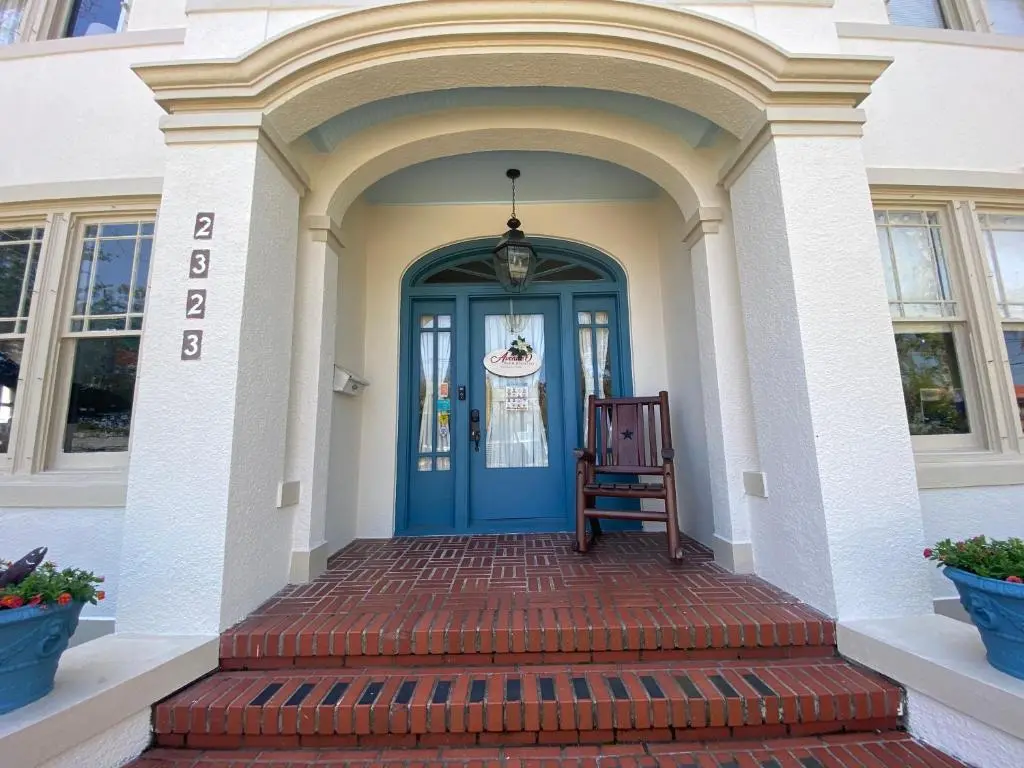 Brick steps, rocking chair and blue front door at the entrance of Avenue O Bed and Breakfast in Galveston