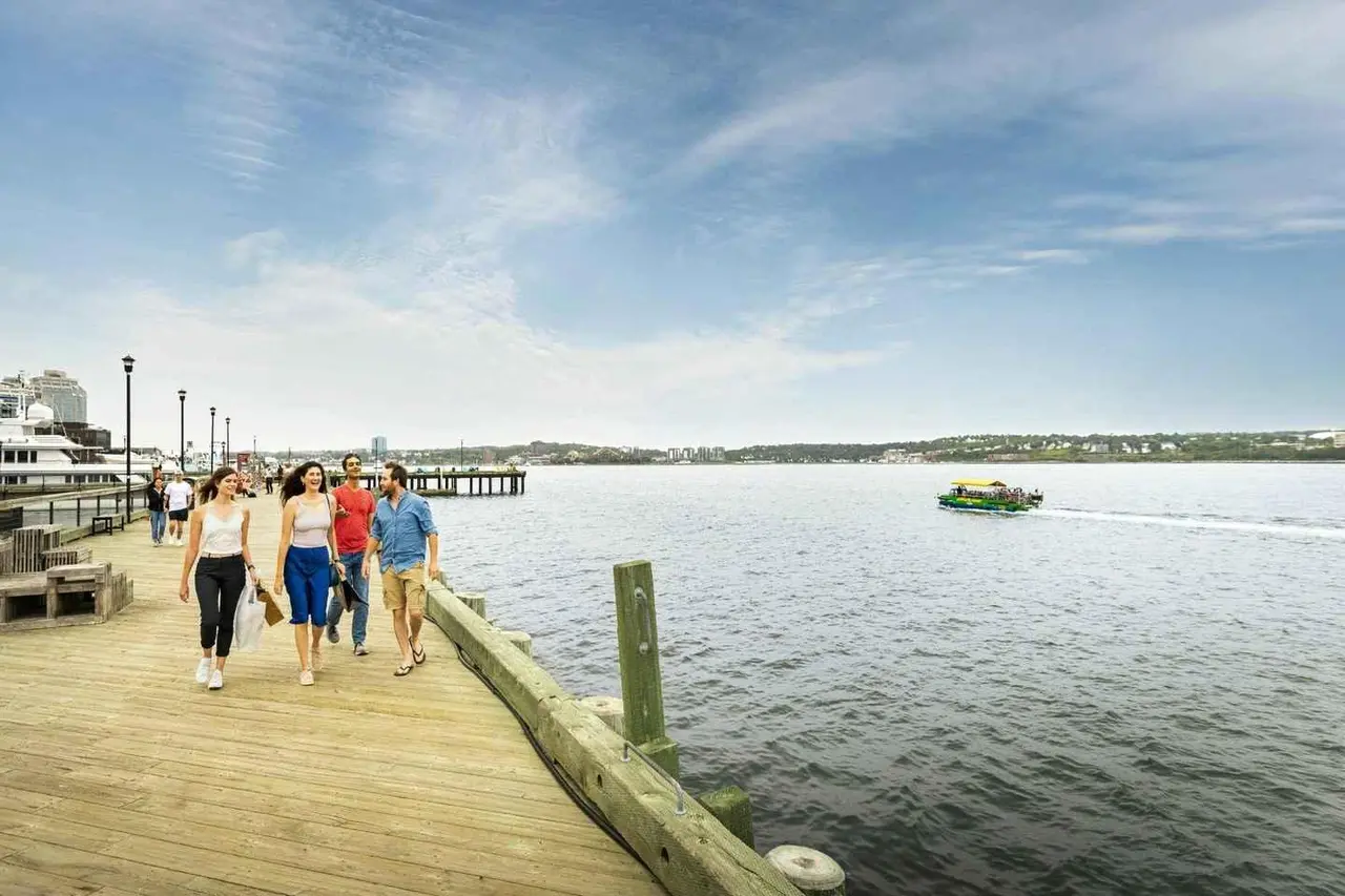 People strolling a wooden boardwalk beside the calm harbour