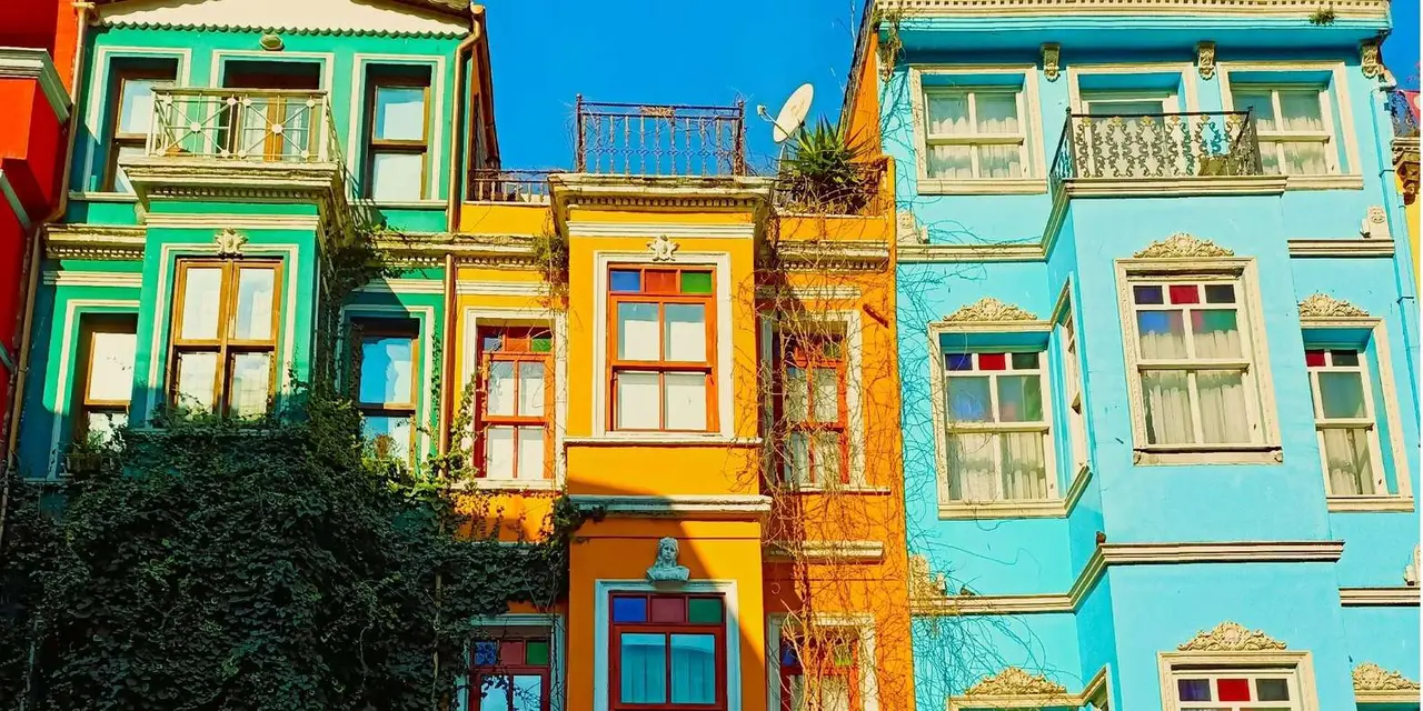 A row of houses painted yellow, turquoise and green on a street in Balat