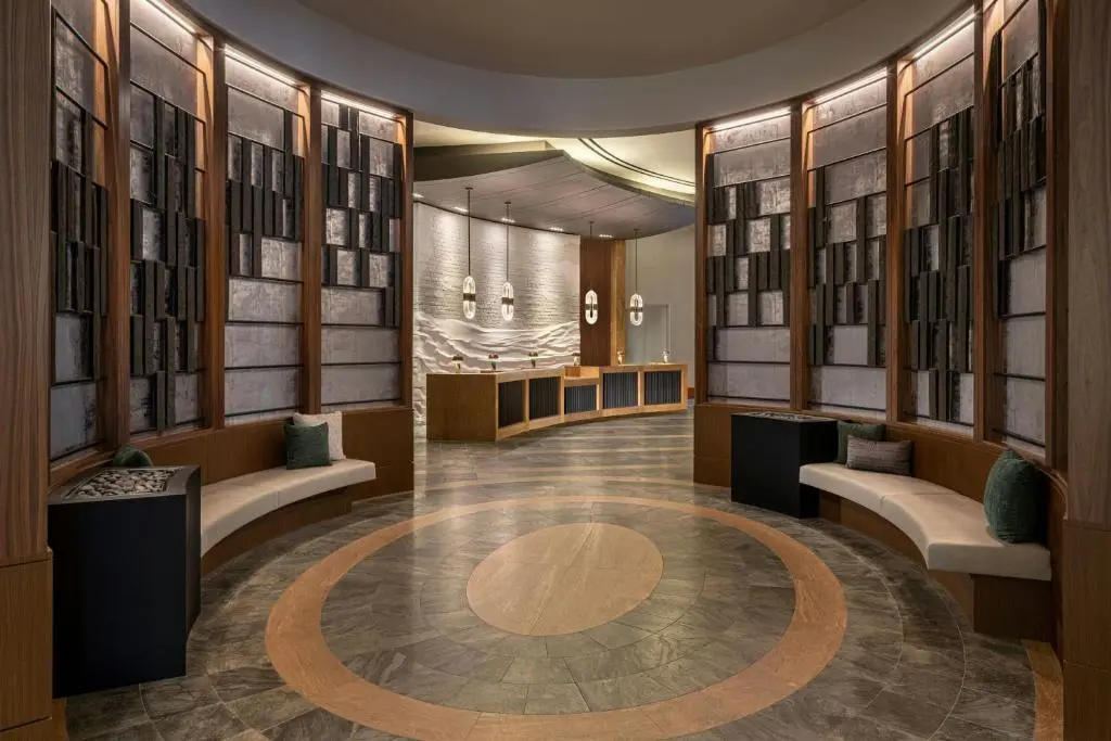 The Renaissance Boston Seaport's round lobby, with curved wood-and-stone walls, cushioned benches and a marble floor inlaid with a circle