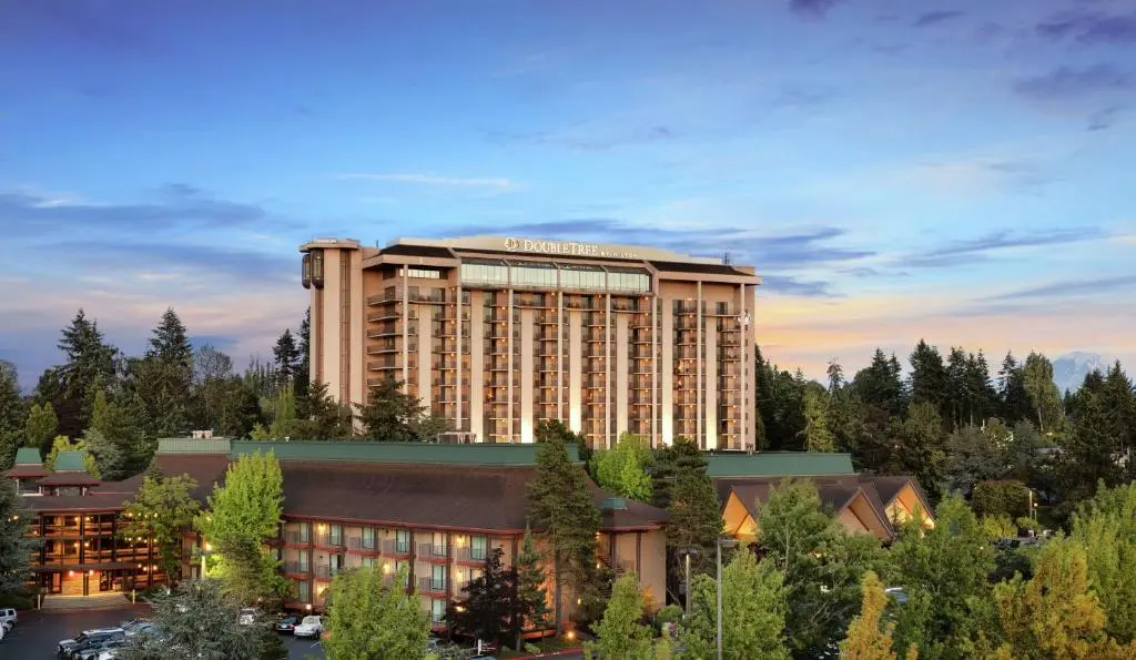 The DoubleTree's tall tower and low timber-roofed wings among evergreens at dusk