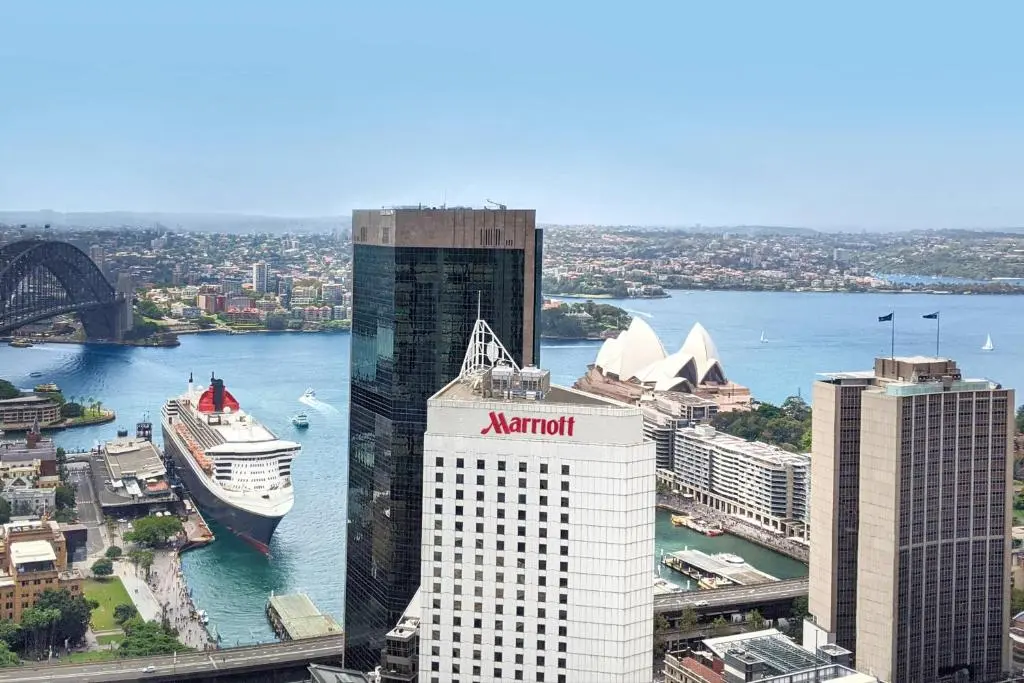Sydney Harbour Marriott tower at Circular Quay with a cruise ship docked at the Overseas Passenger Terminal, the Harbour Bridge and the Opera House behind