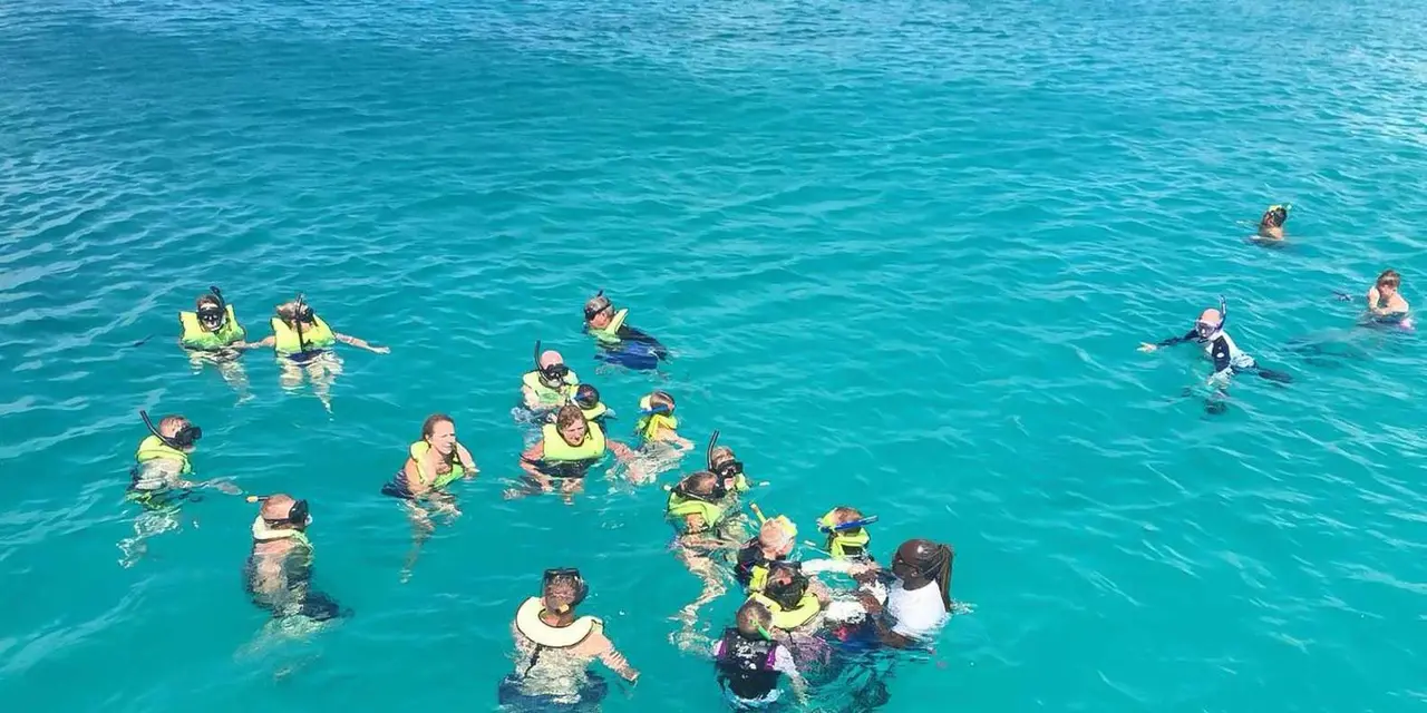 A group of snorkelers in life vests floating on bright turquoise water