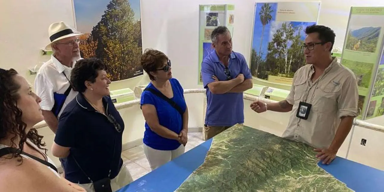 A guide pointing at a raised relief map of the Baja peninsula for a small group in a museum