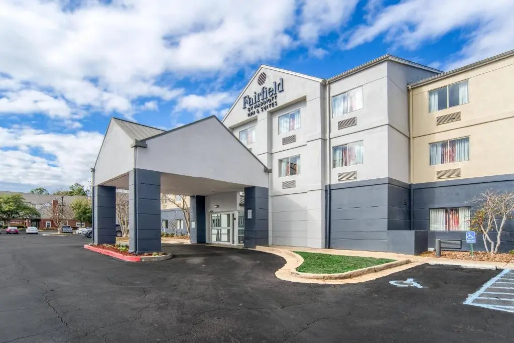 The front of the Fairfield Inn & Suites Mobile, a pale three-storey building with a covered entrance, under a blue sky