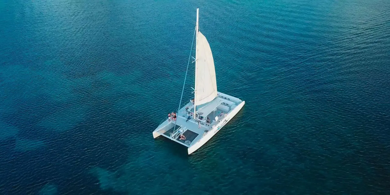 A white sailing catamaran seen from above on deep blue Caribbean water