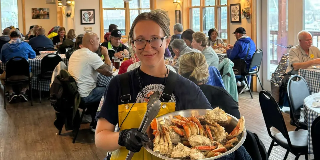 A smiling diner holding a plate of crab legs in a busy dining room