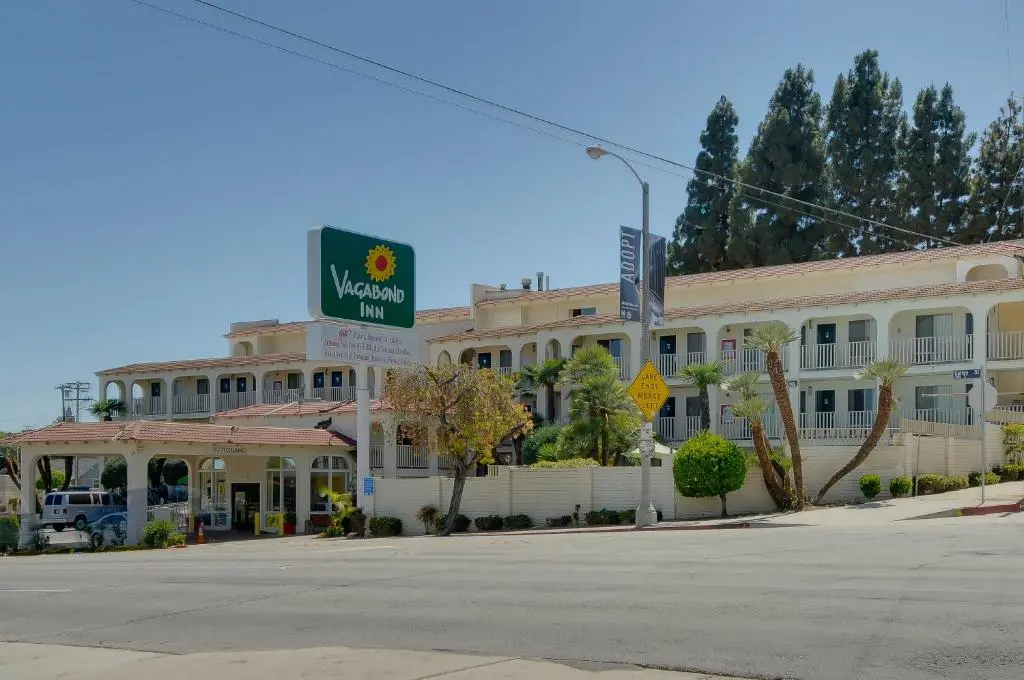 The two-storey cream Vagabond Inn San Pedro with its green sunflower sign, palms and tall pines on Gaffey Street