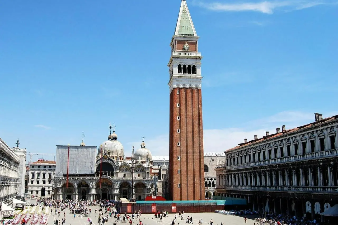 St. Mark's Square with the tall brick bell tower and the domes of the Basilica under a blue sky