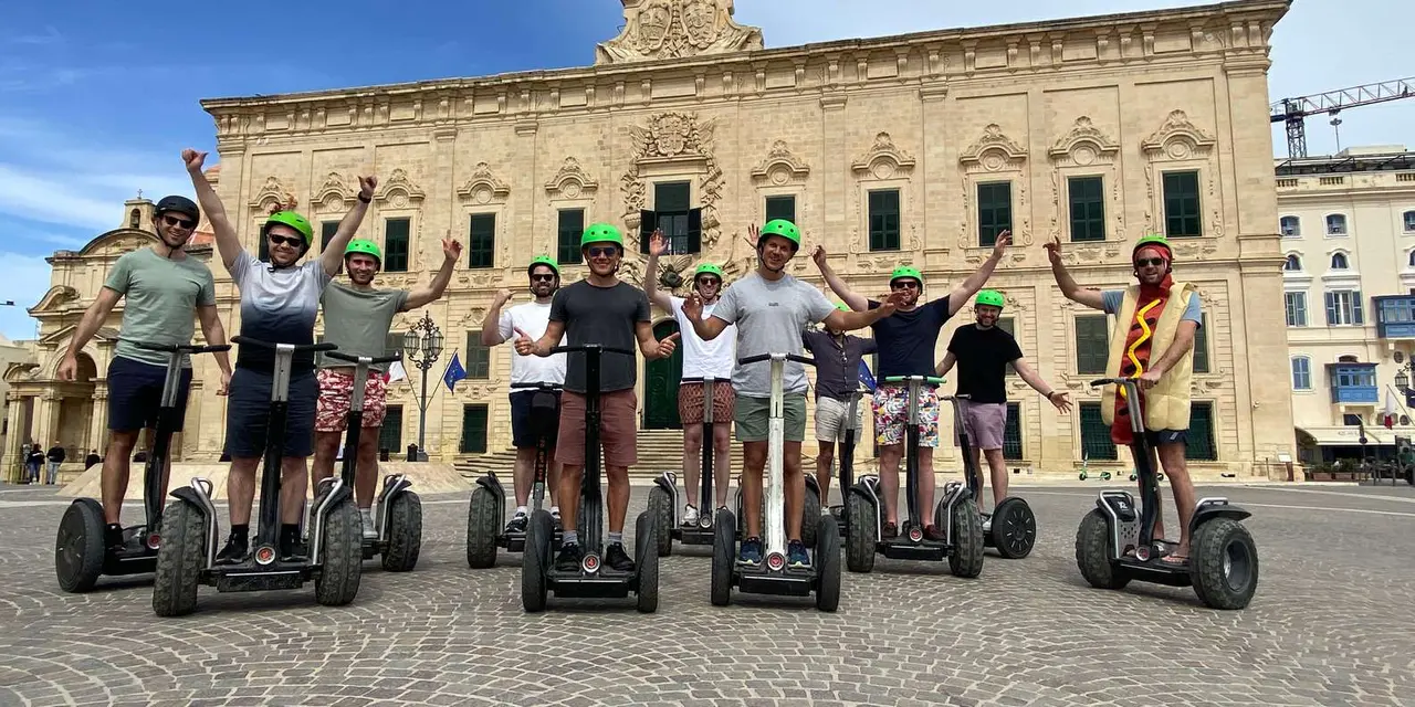 A group on Segways lined up in front of a grand limestone palace in Valletta