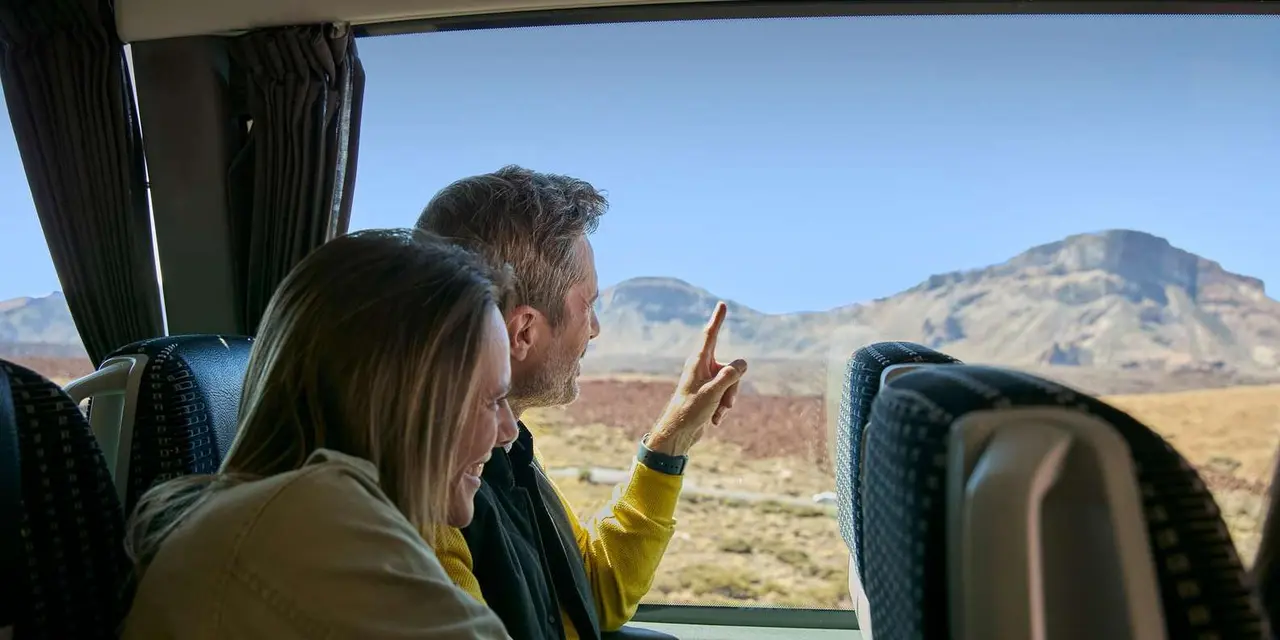 Two travelers by a coach window, one pointing toward a flat-topped desert mountain under a clear sky