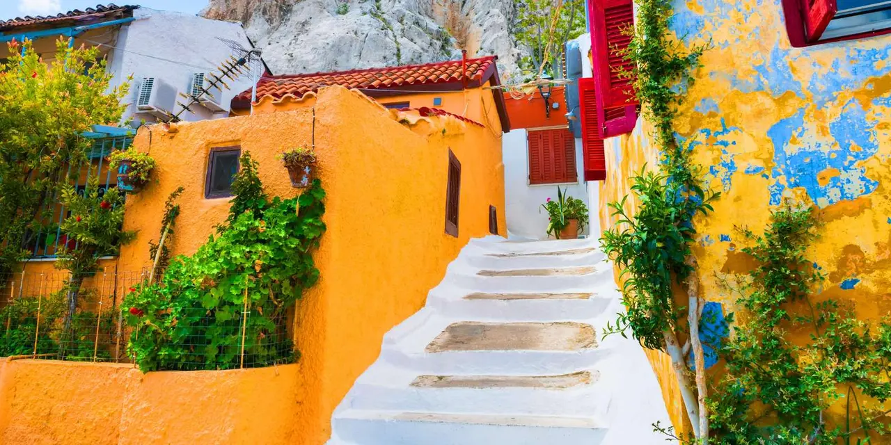 A narrow lane in Anafiotika with whitewashed steps, orange walls, potted plants and climbing greenery