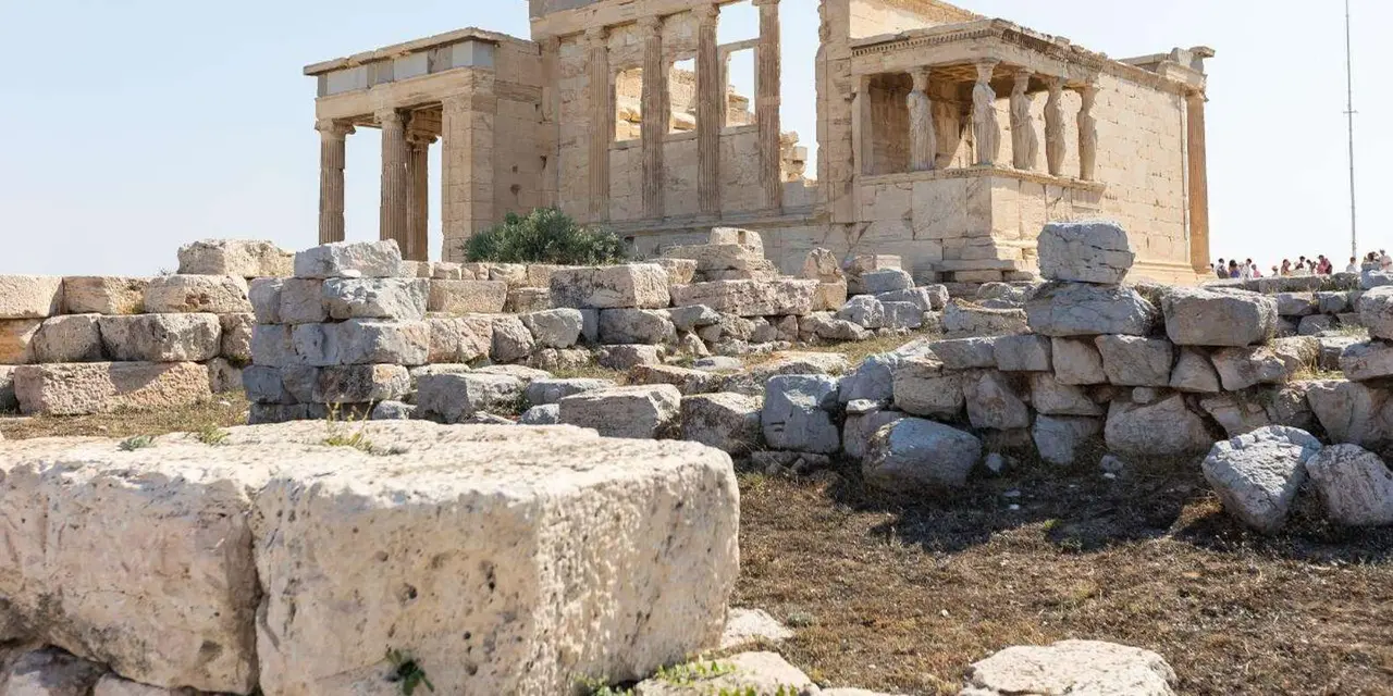 The Erechtheion's Porch of the Caryatids behind scattered marble blocks on the Acropolis