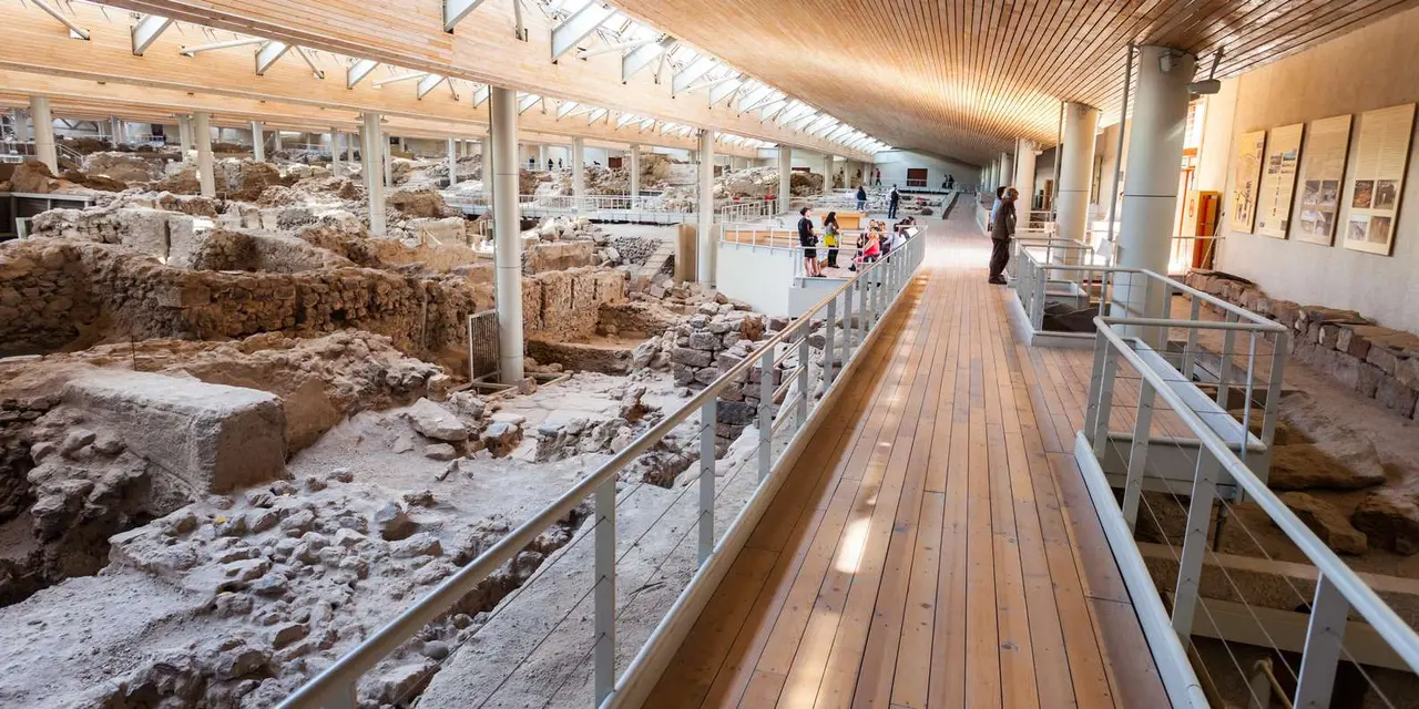 Wooden walkways above excavated stone walls under the roof at the Akrotiri archaeological site