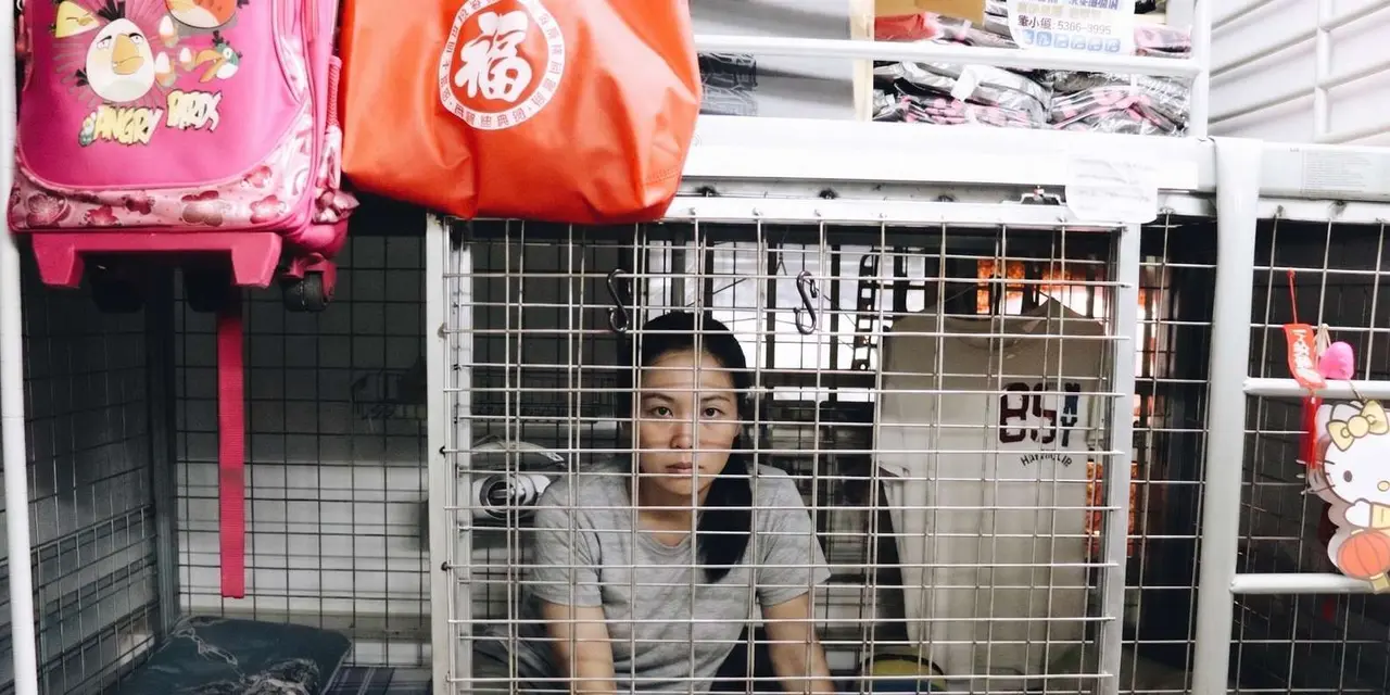 A woman sitting inside a wire-mesh cage bed
