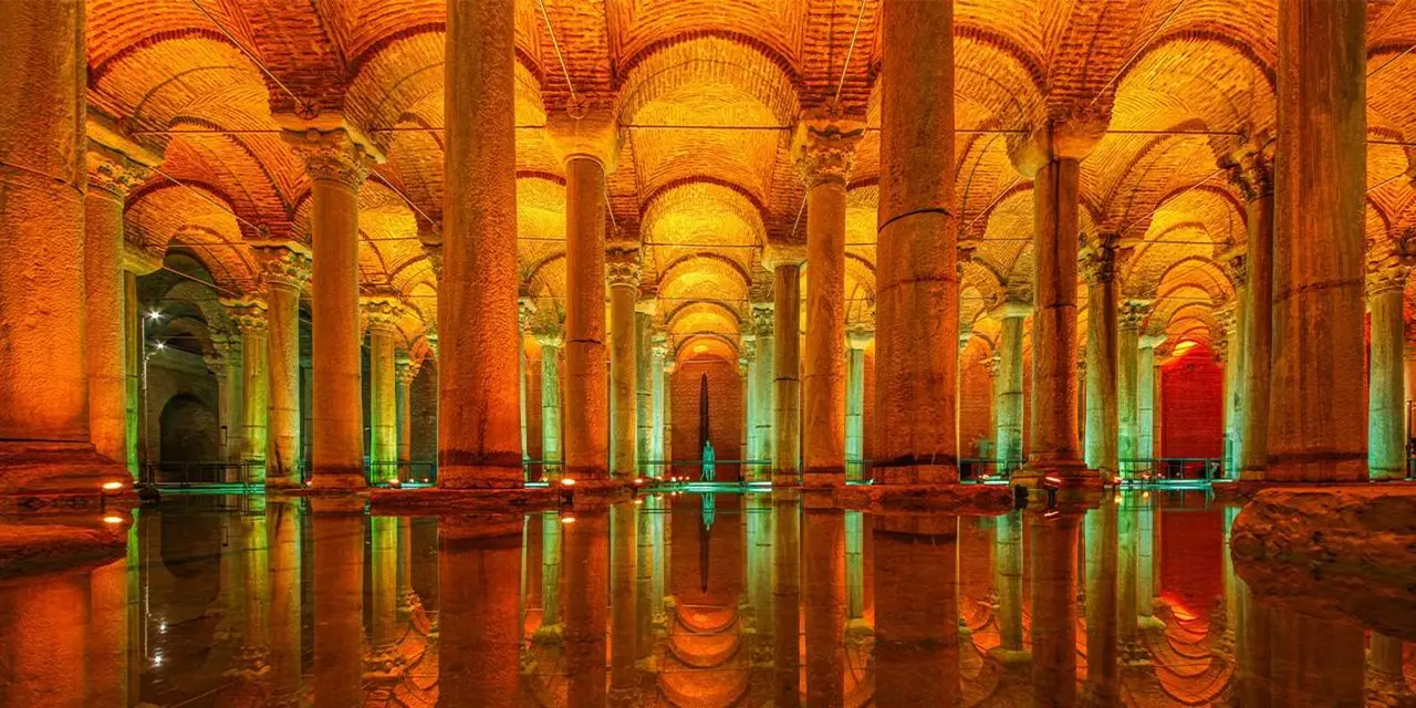 Rows of marble columns lit orange and reflected in the shallow water of the Basilica Cistern