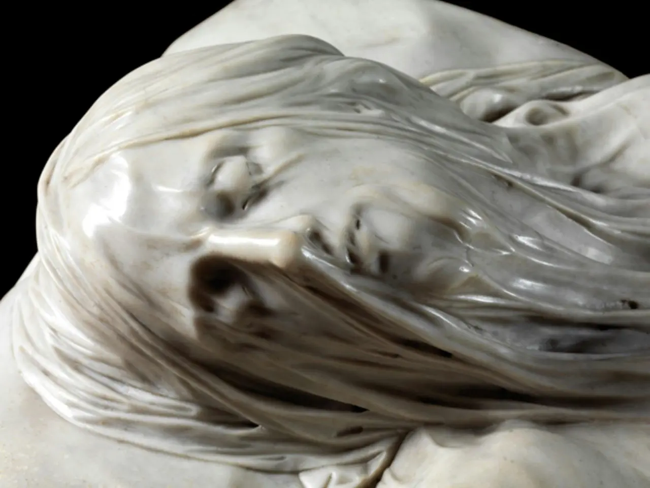 A close-up of the marble face of the Veiled Christ sculpture beneath its carved, see-through veil