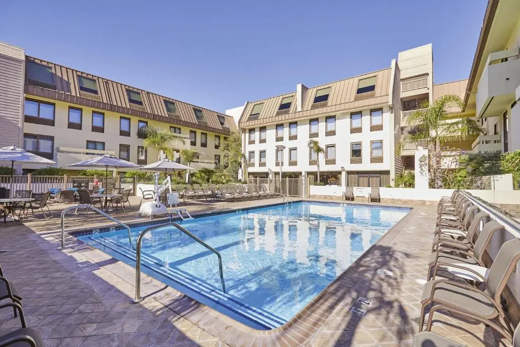 The Riu Plaza Fisherman's Wharf courtyard pool with loungers and umbrellas, framed by the hotel's cream-coloured wings