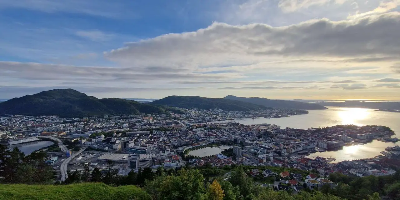 Bergen and its harbour seen from Mount Fløyen at sunset, with islands and the fjord beyond