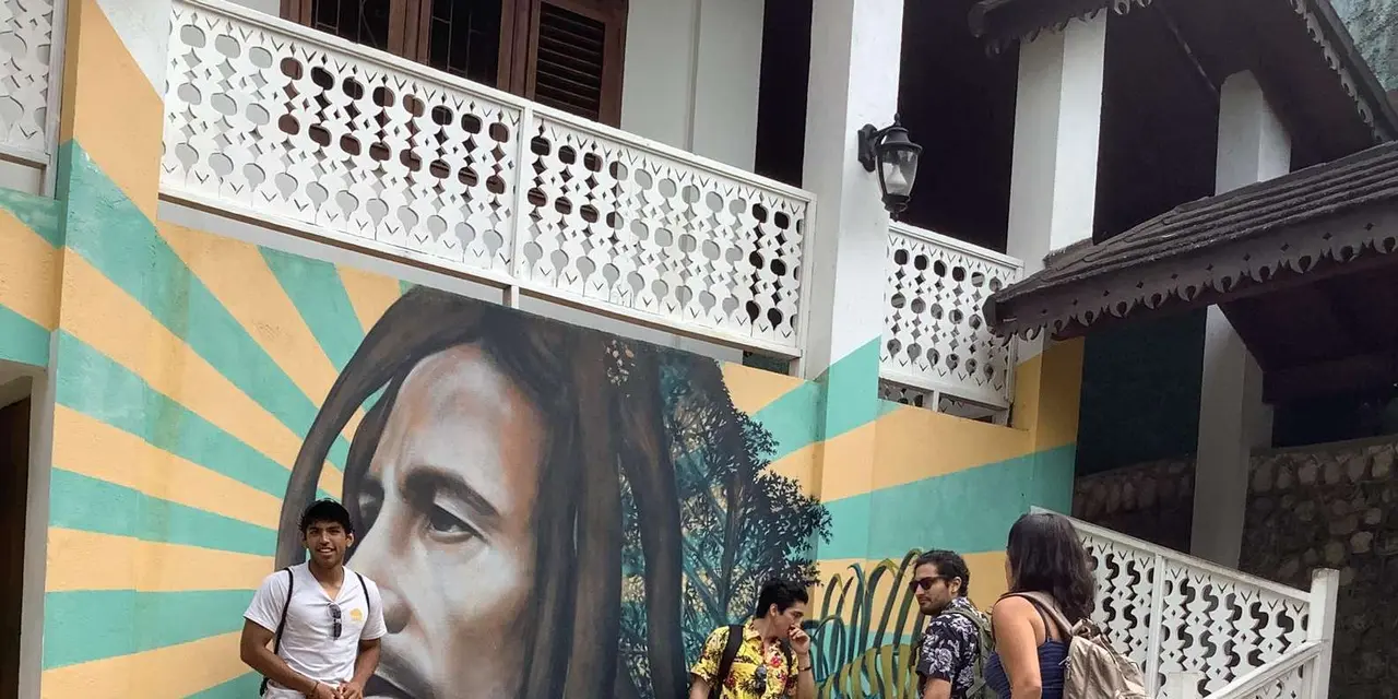 Visitors standing in front of a Bob Marley mural on a balconied building