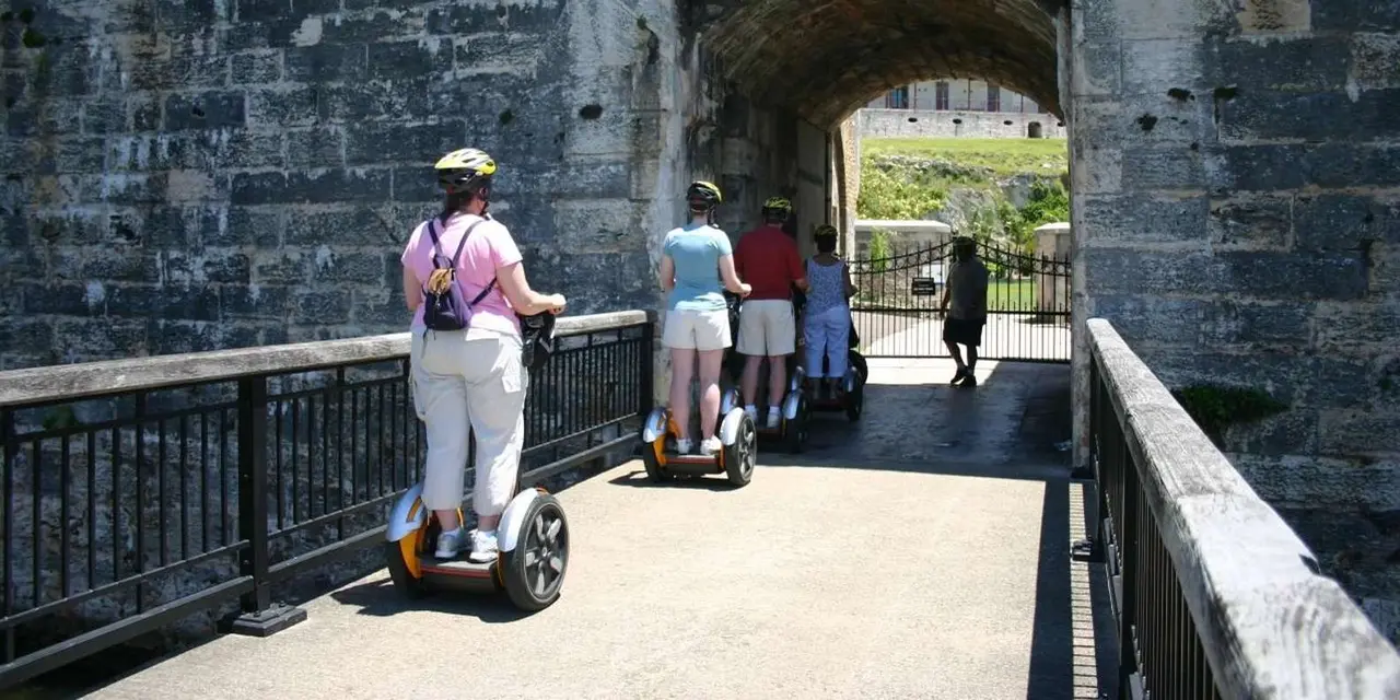 Riders on Segways coming through a stone archway in the Dockyard walls