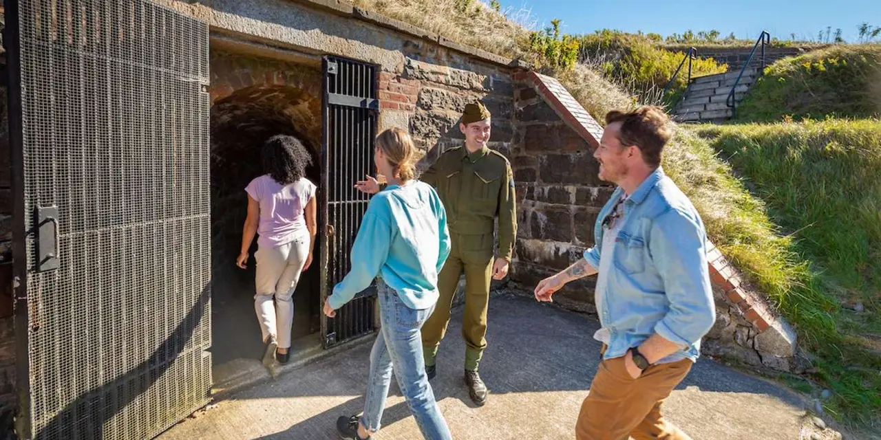 Visitors walking out of a stone tunnel in the Georges Island fort