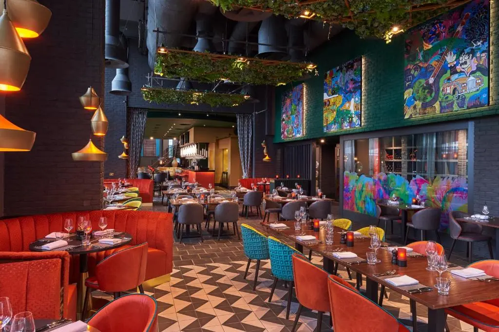 Malmaison Liverpool's restaurant, with orange banquettes, colourful murals and greenery hanging from the ceiling