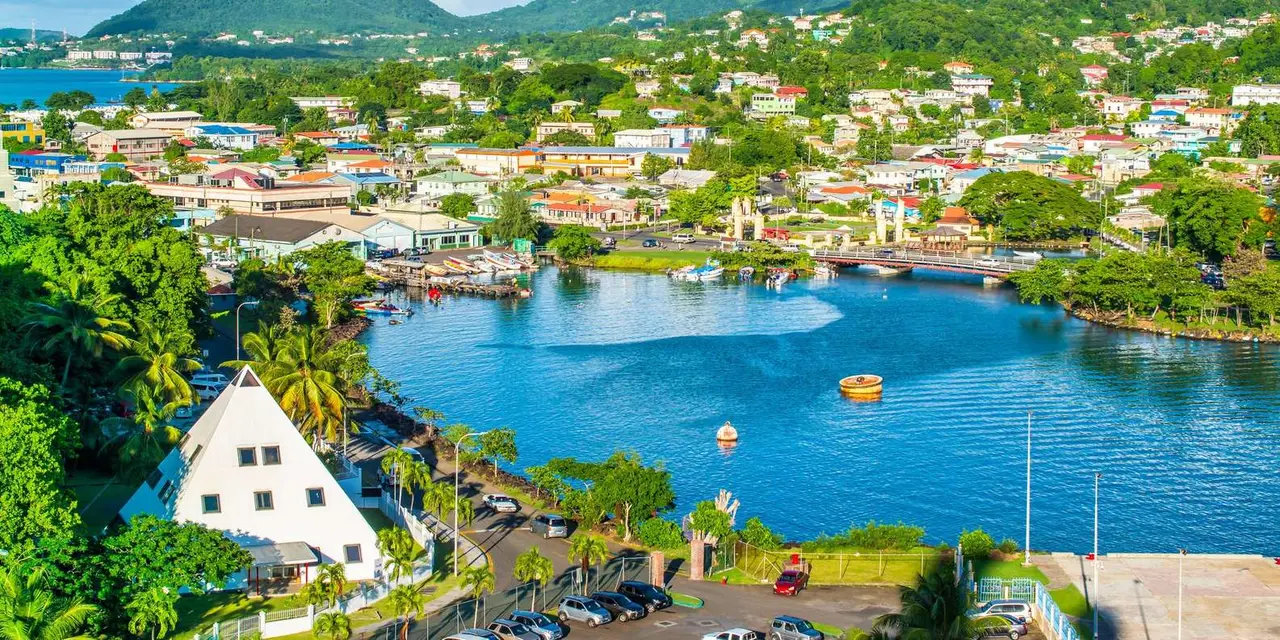 An aerial view of a harbour town with red rooftops around a blue inlet