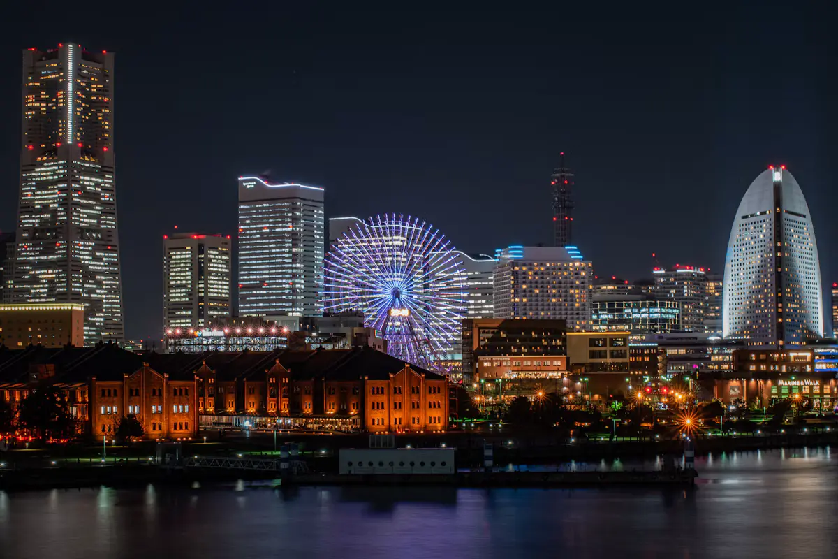 Yokohama's Minato Mirai skyline at night with Landmark Tower, the lit Cosmo Clock 21 ferris wheel and the Red Brick Warehouse across the harbor