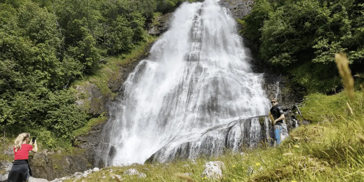 A broad waterfall tumbling over rock with a person standing at its edge