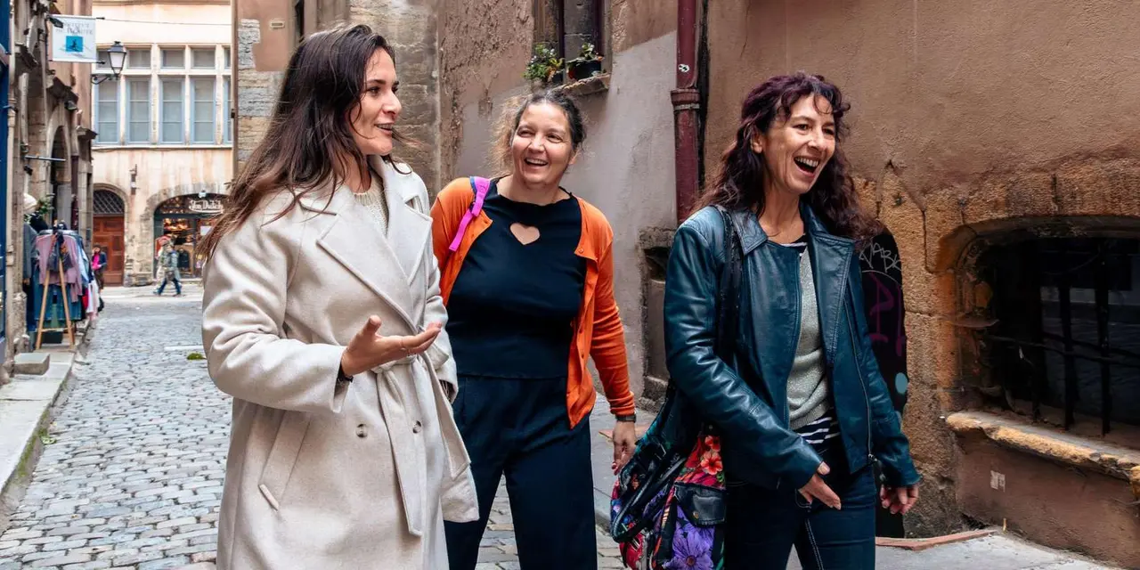 Three women laughing as they walk along a cobbled old-town street