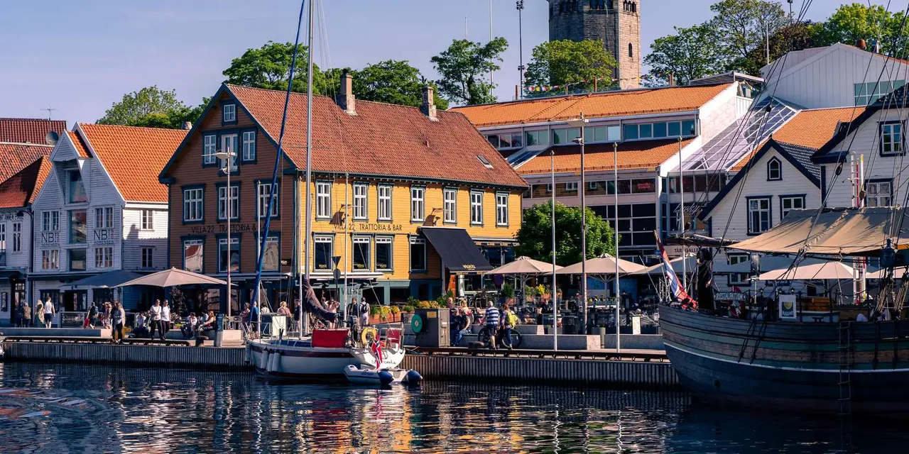 A yellow wooden waterfront building with café umbrellas and moored boats in front