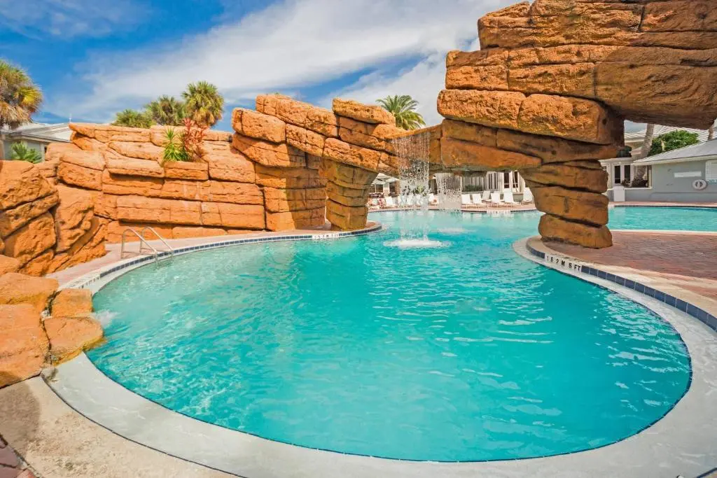 The Radisson Resort at the Port's lagoon pool, with turquoise water, a sandstone-style rock waterfall and arch, and palm trees under a blue sky
